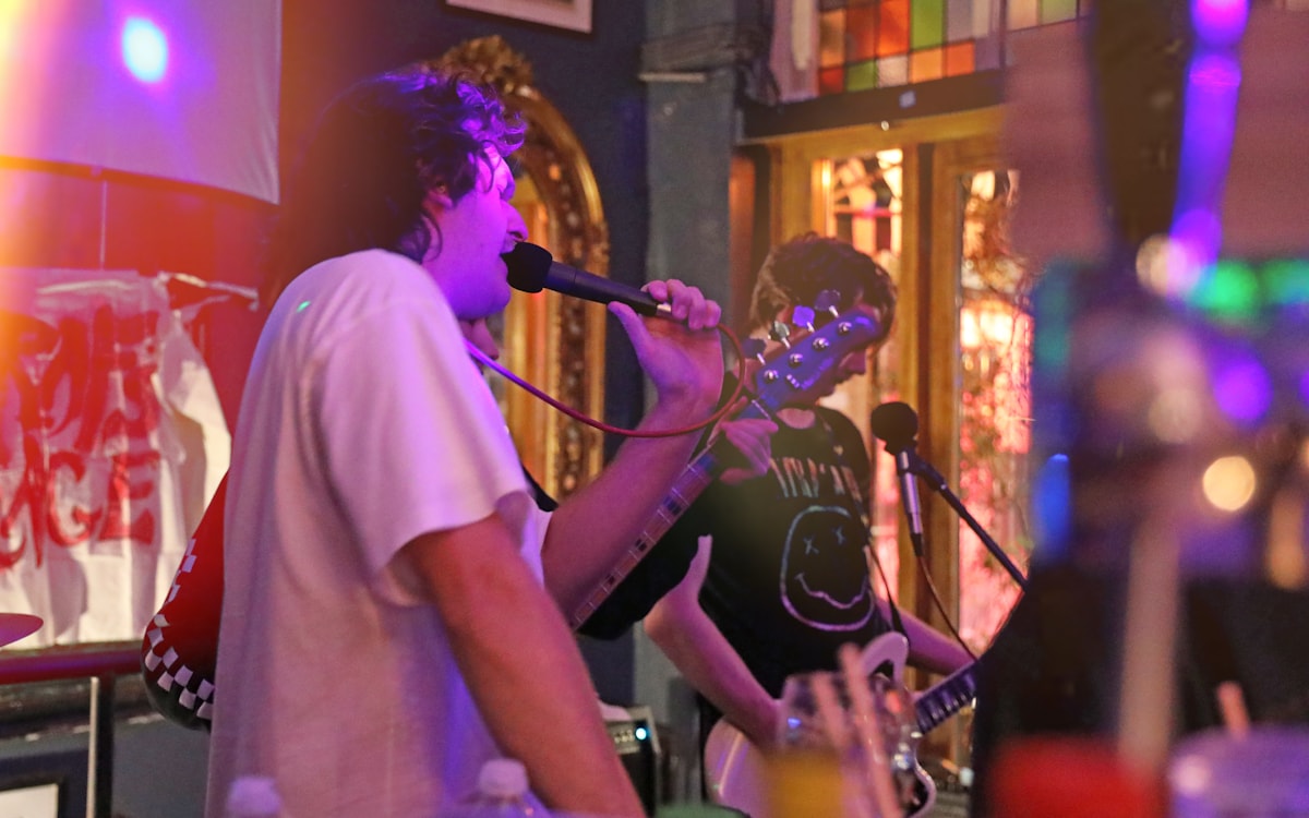 Performer playing acoustic guitar on stage under warm stage lighting at a live music venue